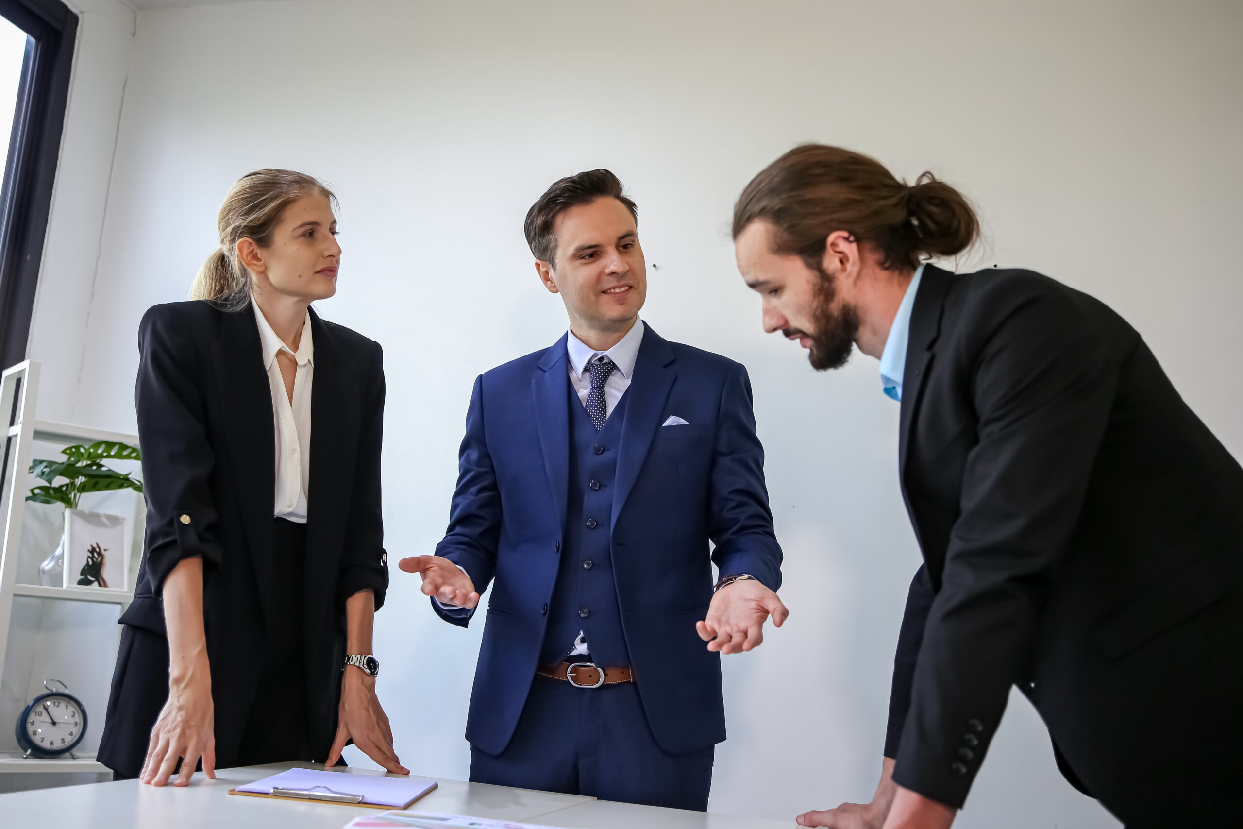 Três homens de terno negociando em uma sala fechada